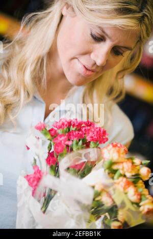 Primo piano di una giovane donna che guarda un bouquet di fiori Foto Stock