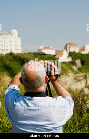 Vista posteriore di un uomo che filma con la sua videocamera domestica, Biarritz, Paesi Baschi, Pirenei Atlantici, Aquitania, Francia Foto Stock