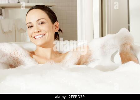 Ritratto di una giovane donna reclinata in un bagno di bolla Foto Stock