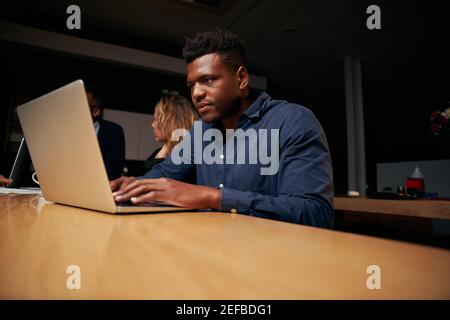 Ritratto di un giovane e serio uomo d'affari che usa un computer portatile in ufficio Foto Stock