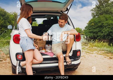 Uomo e donna che hanno pic-nic in un tronco del loro auto Foto Stock