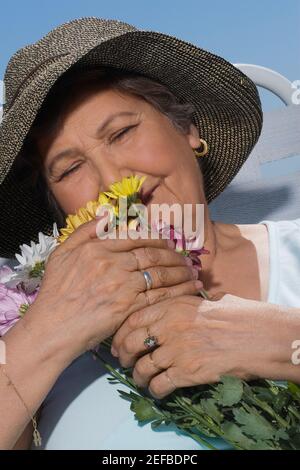 Close up di una donna anziana che odora mazzo di fiori Foto Stock