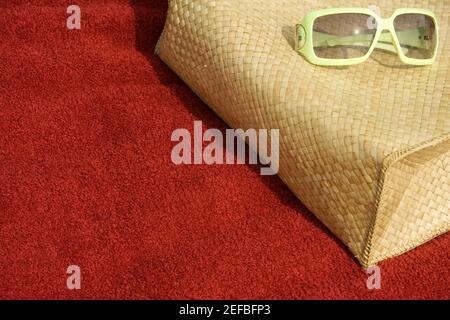 Vista ad alto angolo degli occhiali da sole che giacciono sopra una borsa Foto Stock