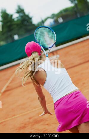 Vista posteriore di una donna mid adult che gioca a tennis con un'altra persona Foto Stock