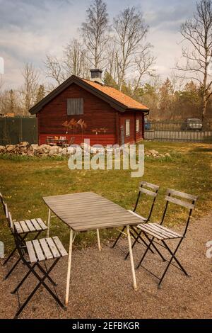 Piccolo cottage in un ambiente rurale, con tavolino da caffè e sedie. Foto Stock