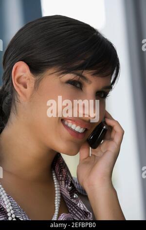 Primo piano di una giovane donna che parla su un telefono cellulare e sorridendo Foto Stock