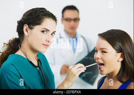 Profilo laterale di una dottoressa che esamina una bocca di girlÅ½s con un depressore della lingua Foto Stock