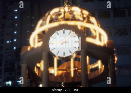 Vista in sezione alta di una torre dell'orologio illuminata di notte, Hong Kong, Cina Foto Stock