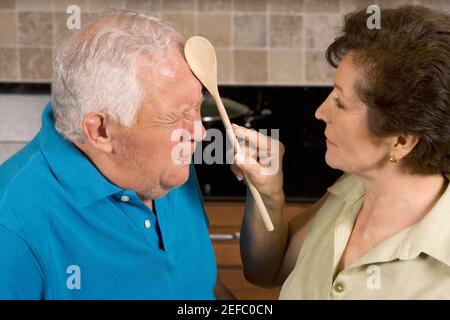 Primo piano di una donna anziana che colpisce un uomo anziano con un mestolo Foto Stock