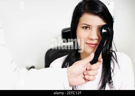 Primo piano di una doctorÅ½s mano che esamina un occhio giovane womanÅ½s Foto Stock