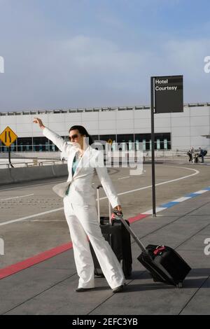 Una donna d'affari che si trova in città per un taxi fuori dall'aeroporto Foto Stock