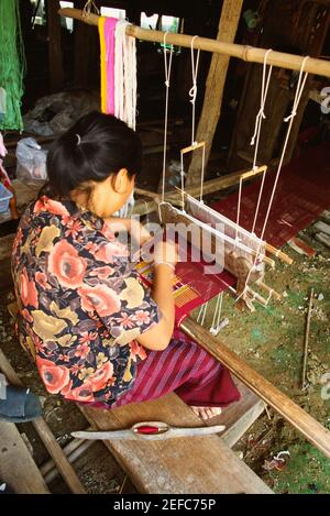 Vista ad alto angolo di una giovane donna che tesse su un telaio tradizionale, Sukhothai, Thailandia Foto Stock