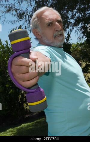 Profilo laterale di un uomo anziano che si esercita con manubri Foto Stock