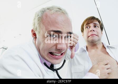 Close up di un medico di sesso maschile che esamina un paziente con un stetoscopio e facendo un segno di pollice giù Foto Stock