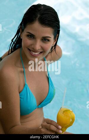 Vista ad alto angolo di una giovane donna che tiene un drink in una piscina Foto Stock