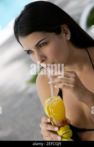 Primo piano di una giovane donna che sorseggia una bevanda da un bicchiere Foto Stock