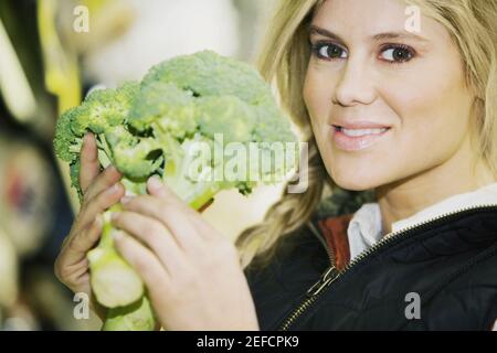 Ritratto di una giovane donna che tiene un broccoli Foto Stock
