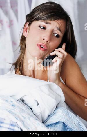 Close up di una giovane donna che parla al telefono e. portare abiti Foto Stock