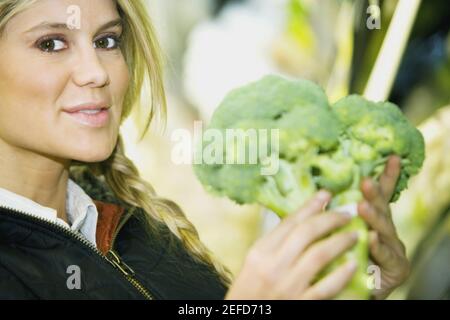 Ritratto di una giovane donna che regge broccoli Foto Stock