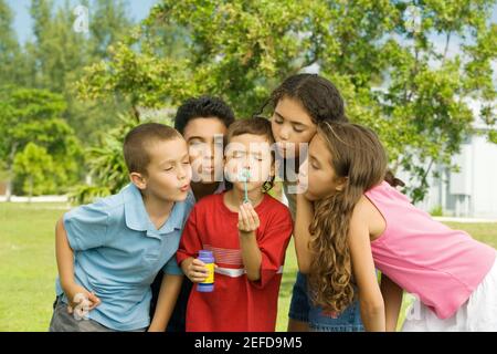 Ragazzi e ragazze che soffiano i wands della bolla Foto Stock