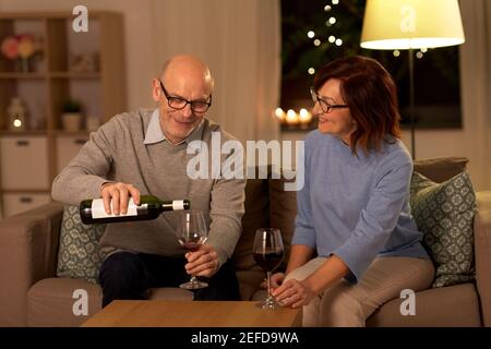 felice coppia anziana che beve vino rosso a casa Foto Stock