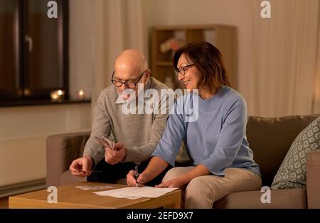 coppia anziana con le fatture che contano i soldi a casa Foto Stock