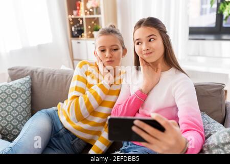 felici le ragazze che prendono selfie con lo smartphone a casa Foto Stock