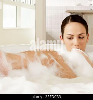 Primo piano di una giovane donna in un bagno di bolla Foto Stock