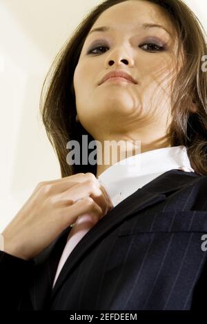 Vista ad angolo basso di una donna d'affari che regola la sua cravatta Foto Stock
