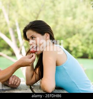 Primo piano di un giovane che alimenta una giovane donna a. fragola Foto Stock