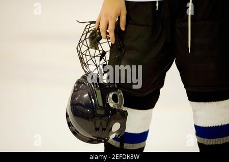 Vista in sezione intermedia di un giocatore di hockey su ghiaccio che tiene un casco Foto Stock