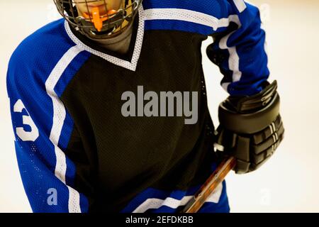 Vista in sezione intermedia di un giocatore di hockey su ghiaccio che tiene un bastone per hockey su ghiaccio Foto Stock