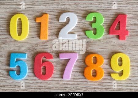 Numeri colorati in schiuma su sfondo di legno Foto Stock