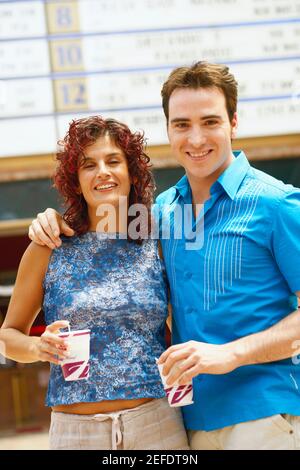 Ritratto di una donna matura e di un mid adult tenere le tazze monouso in un bar Foto Stock