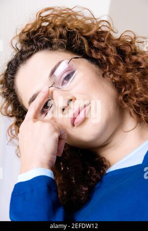 Ritratto di una giovane donna regolando i suoi occhiali Foto Stock
