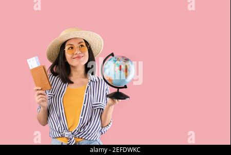 Vacanza da sogno. Ritratto di entusiasta viaggiatore asiatico felice in possesso di passaporto con biglietti d'imbarco aereo e globo, indossare occhiali da sole, looki Foto Stock
