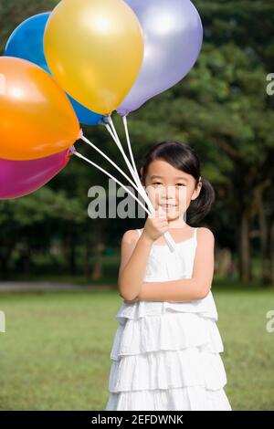 Ritratto di una ragazza che tiene palloncini in un parco Foto Stock