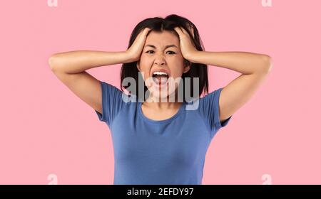 Concetto di reazioni. Arrabbiata donna asiatica gridando e afferrando la testa. Furiosa signora urlando forte, stanca dei suoi problemi, esprimendo emozioni negative, iso Foto Stock