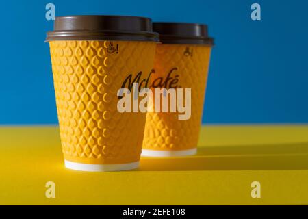 Ucraina, Kiev - 17 febbraio 2021: Bicchiere giallo di caffè da McDonald's. Bicchiere di carta McCafe. Tazza di caffè offee sul tavolo con ombre. Menu in fast food Foto Stock