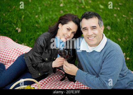 Ritratto di una coppia di mezza età seduta su un picnic coperta e sorridente Foto Stock