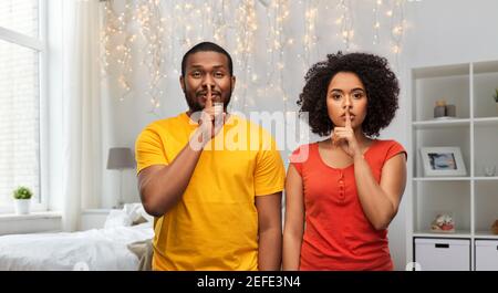 felice coppia afroamericana che fa il gesto di hush Foto Stock
