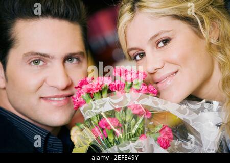 Ritratto di una giovane coppia con bouquet di fiori tra loro Foto Stock