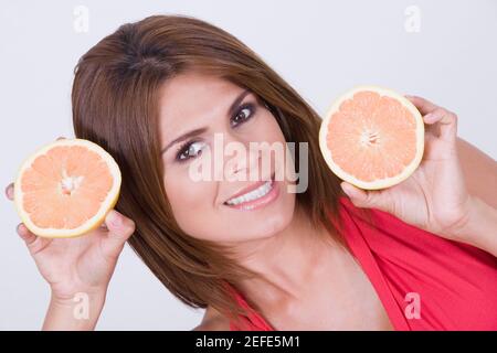 Ritratto di una giovane donna che tiene fette di arance Foto Stock