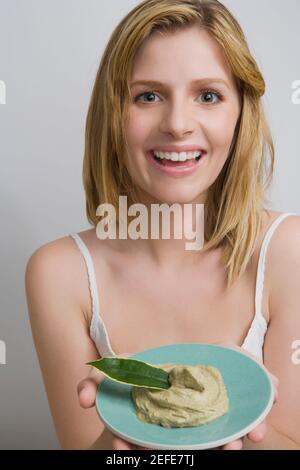 Ritratto di una ragazza adolescente che tiene una ciotola di faccia pack e sorridente Foto Stock