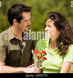 Primo piano di una coppia di metà adulti che tiene un mazzo di fiori che si guardano l'un l'altro Foto Stock