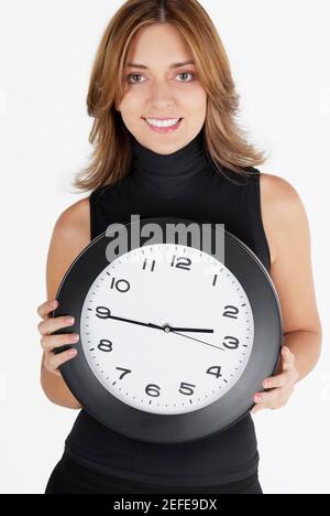 Ritratto di una donna d'affari che tiene un orologio e sorridente Foto Stock