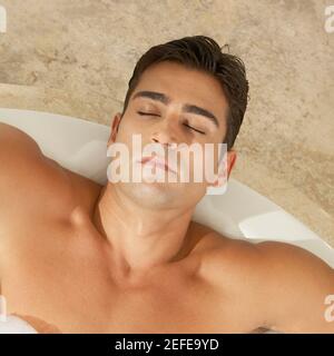 Vista ad alto angolo di un giovane uomo che si rilassa nella vasca da bagno Foto Stock
