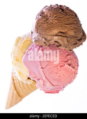 vista dall'alto del vero cono gelato commestibile con 3 diversi cucchiai di gelato (vaniglia, cioccolato, fragola) isolati su sfondo bianco Foto Stock