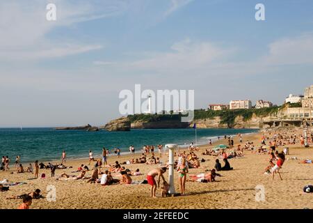 Turisti in spiaggia, Grande Plage, Phare de Biarritz, Biarritz, Francia Foto Stock