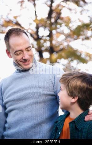 L'uomo medio adulto e suo figlio si guardano l'un l'altro e sorridendo Foto Stock